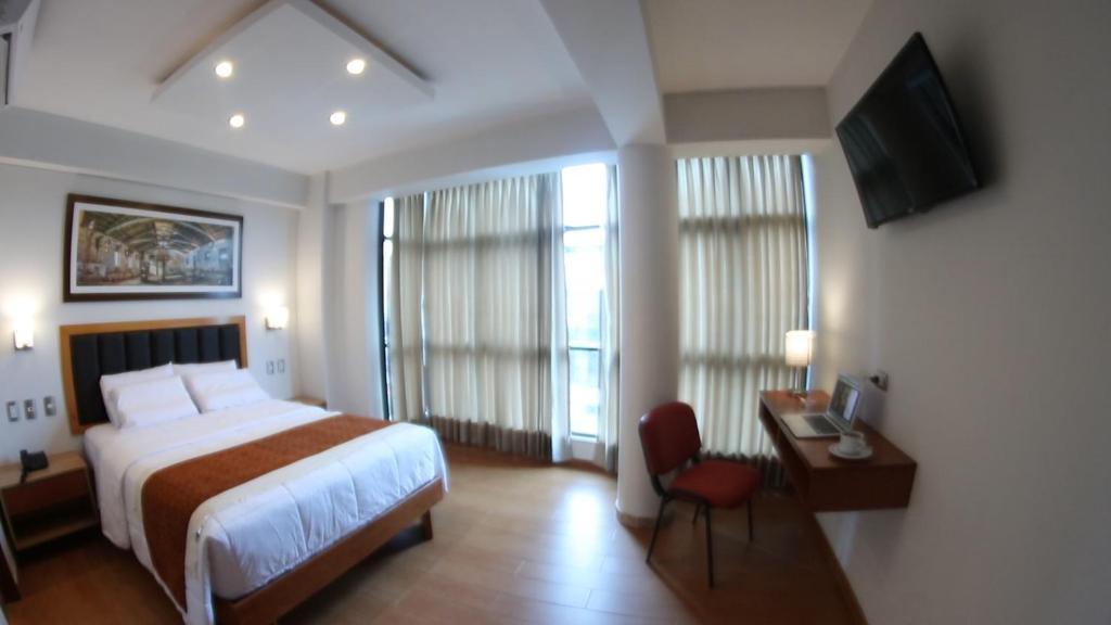 Habitación de hotel con cama, escritorio y TV. en Hotel Ottavis en Chiclayo