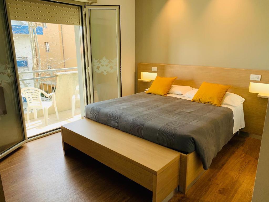 1 dormitorio con 1 cama con almohadas amarillas y balcón en Hotel Liane Riccione, en Riccione