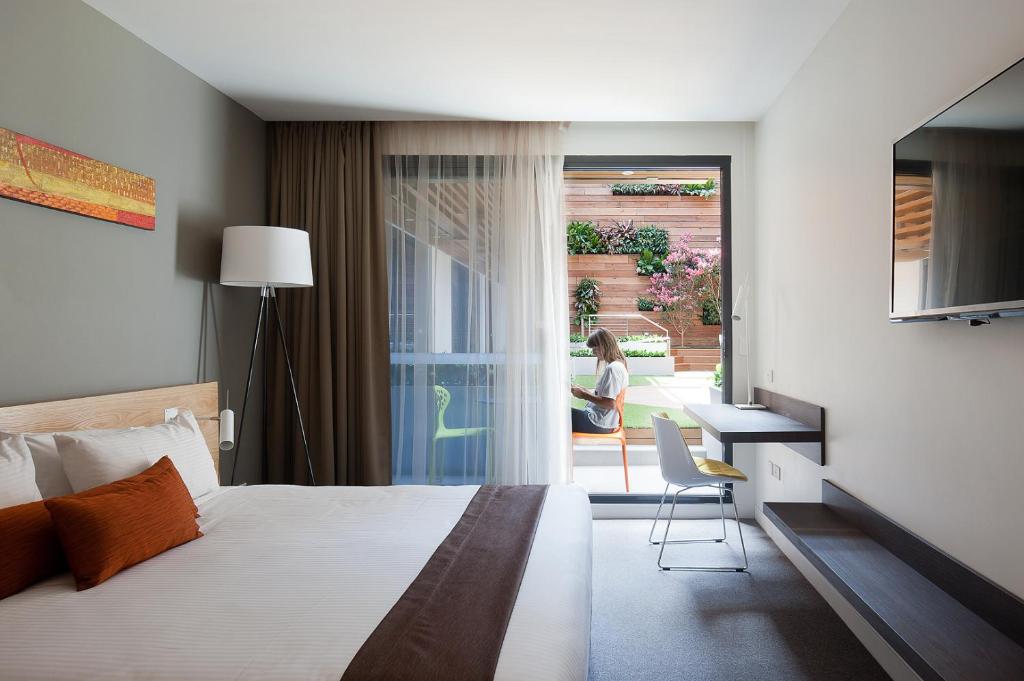 una camera con letto, scrivania e finestra di Jasper Boutique Hotel a Melbourne