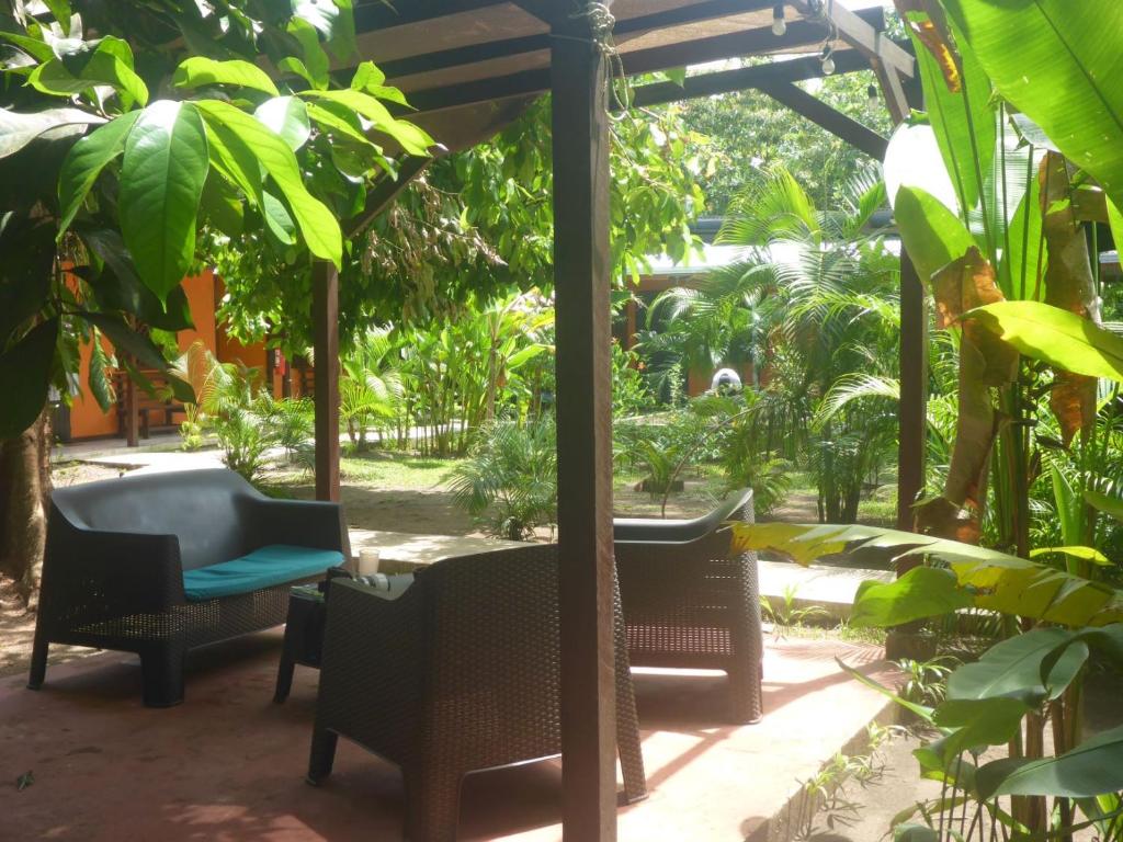 
a patio area with chairs, tables and umbrellas at Aracari Garden Hostel in Tortuguero
