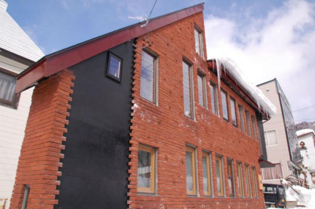 un edificio di mattoni rossi con un colore nero di Nozawa Cottage a Nozawa Onsen