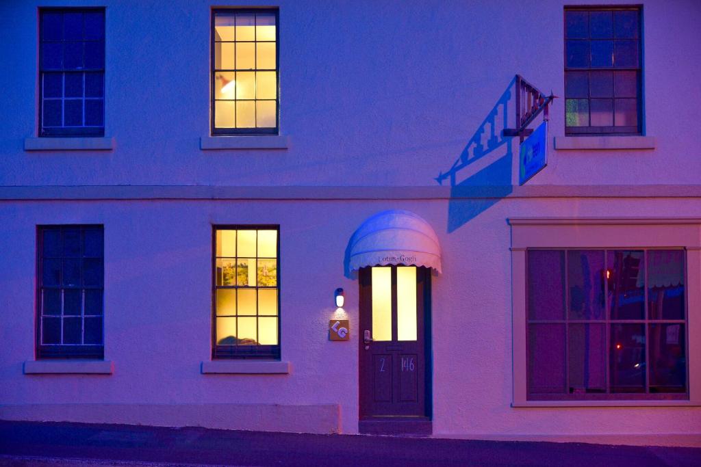 a white house with lit windows and a door at Lotus Gogh Apartment in Hobart