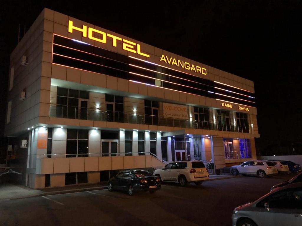 un hotel con coches estacionados en un estacionamiento por la noche en Avangard Hotel, en Krasnodar