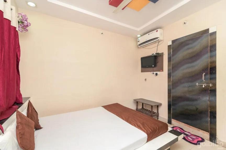 烏賈因的住宿－Hotel Rameshwaram，卧室配有一张床,墙上配有电视。