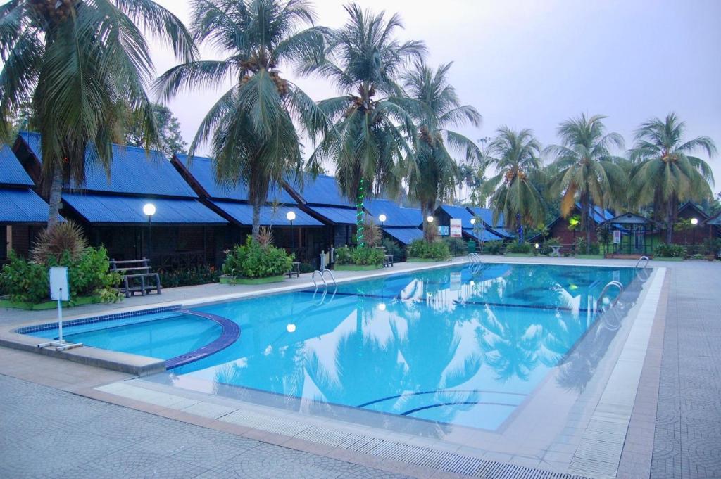 a large swimming pool with palm trees in the background at D'Village Resort Melaka in Melaka