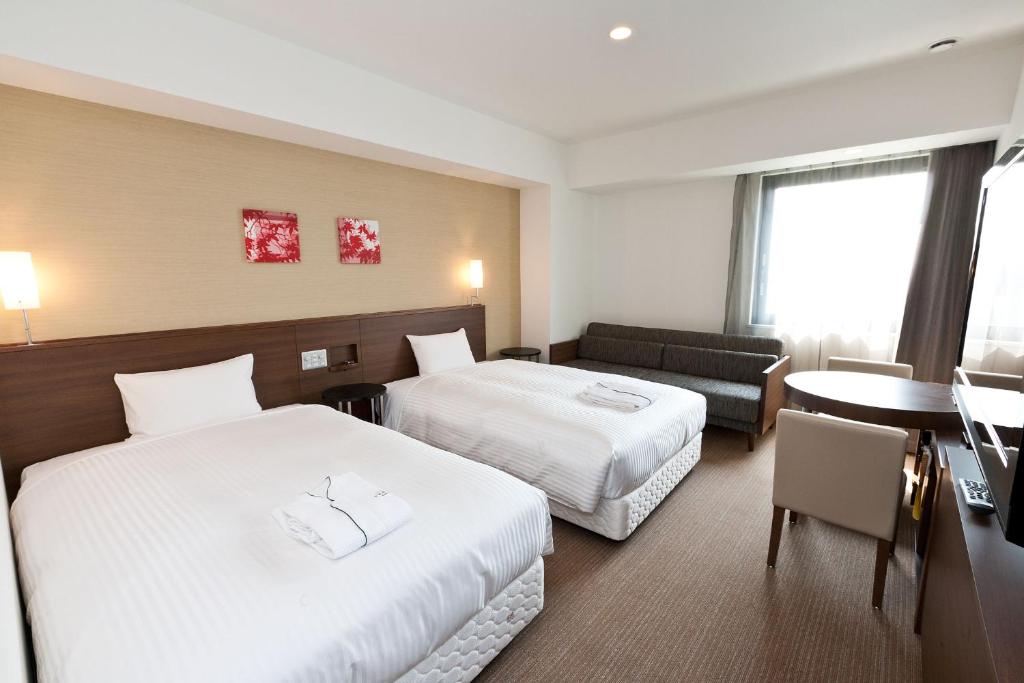una camera d'albergo con due letti e un tavolo di Sotetsu Fresa Inn Chiba Kashiwa a Kashiwa