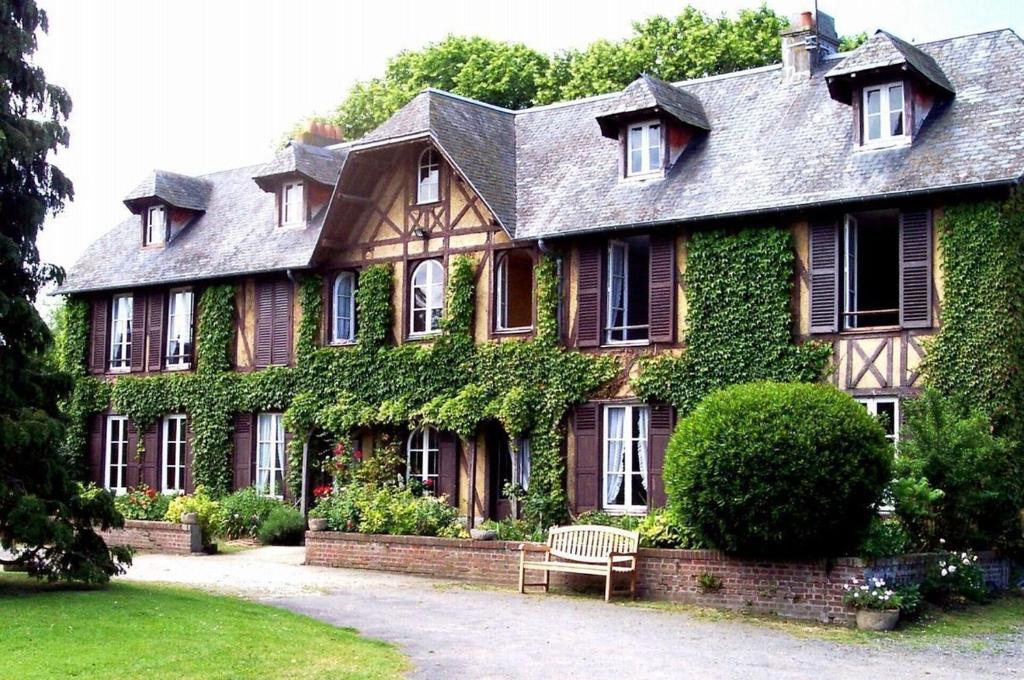 a house covered in ivy with a bench in front of it at LES CHAMPS RABATS in Villers-sur-Mer