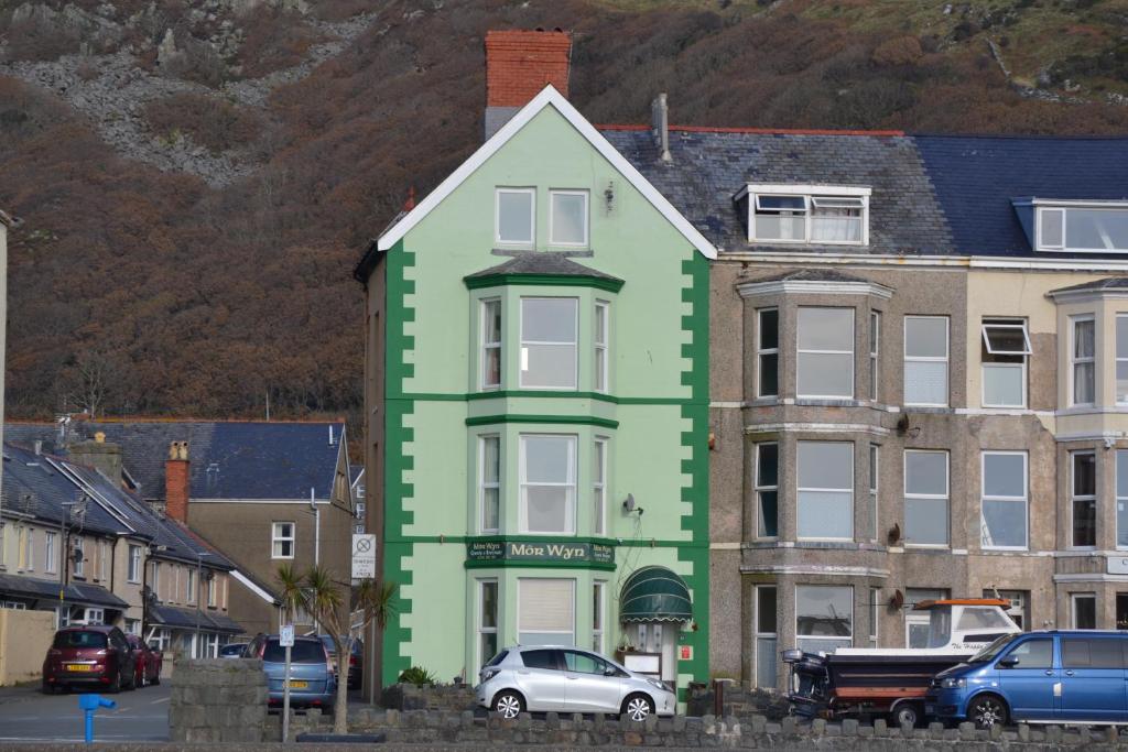 a green building with cars parked in front of it at Môr Wyn Guest House in Barmouth