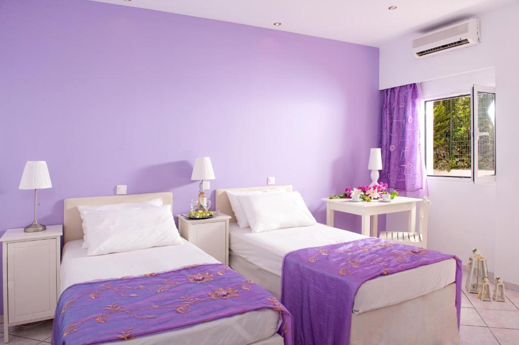 a purple bedroom with two beds and a window at Primavera Beach Hotel Studios & Apartments in Malia