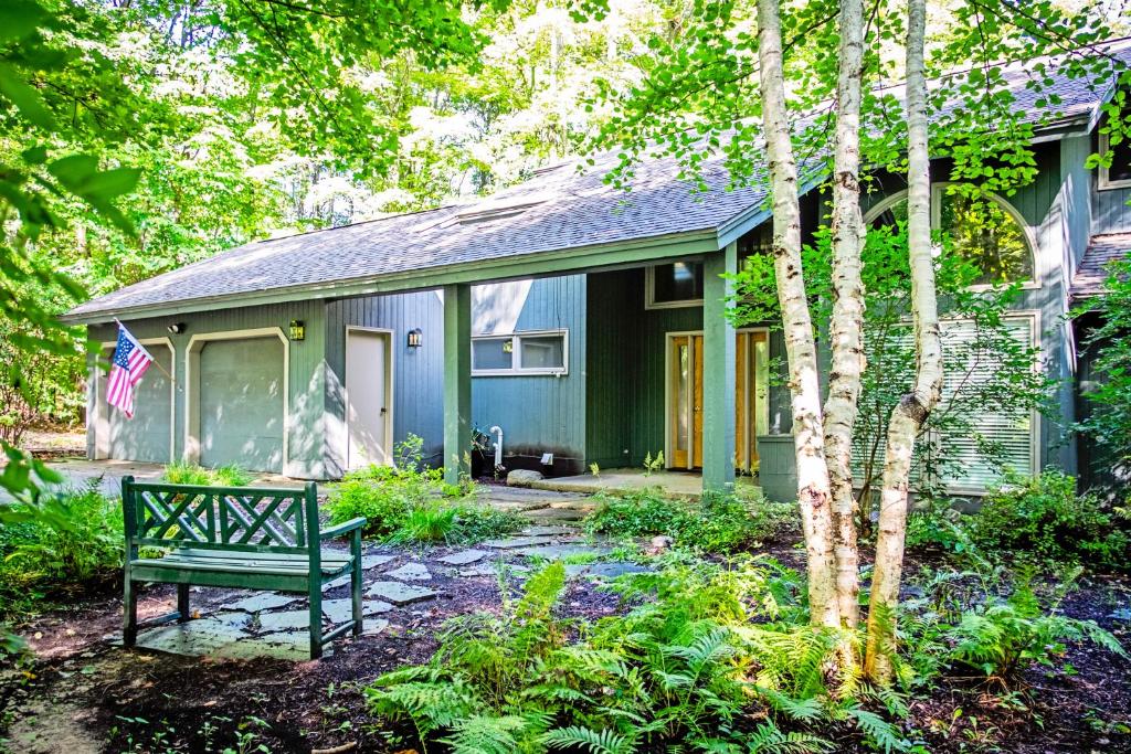 une maison verte avec un banc devant elle dans l'établissement Birchwood: Scenic Sanctuary, à Harbor Springs