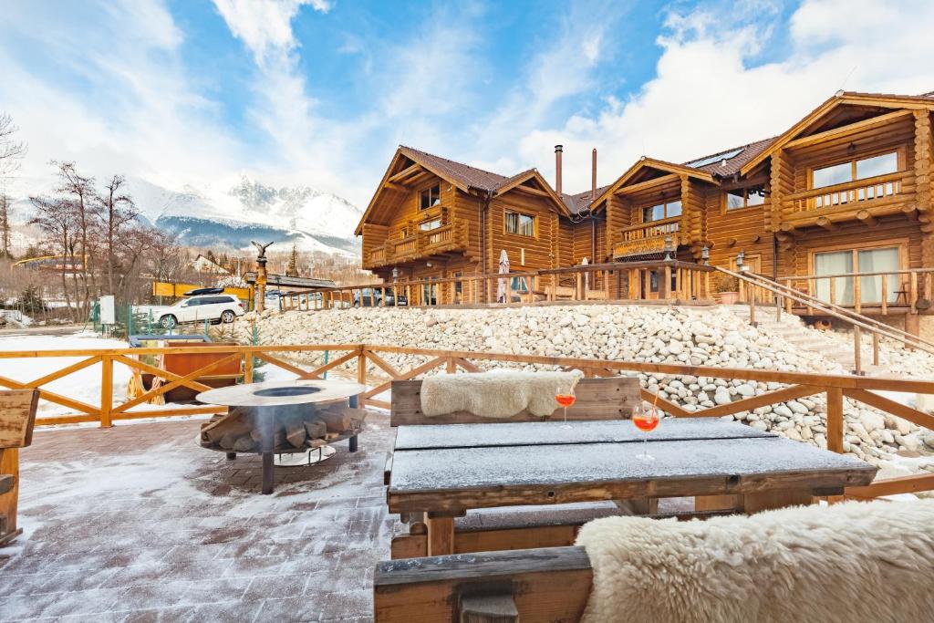 a log cabin in the snow with a table at Wellness Cottage CEDER in Tatranská Lomnica