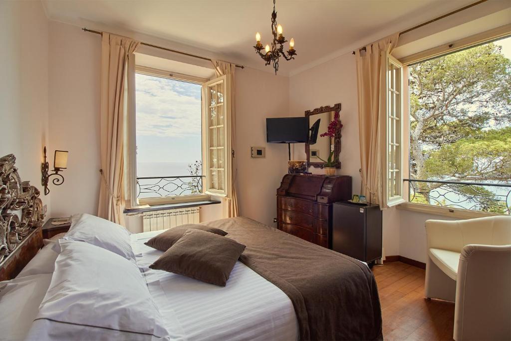 a bedroom with a large bed and two windows at Hotel Punta Est in Finale Ligure