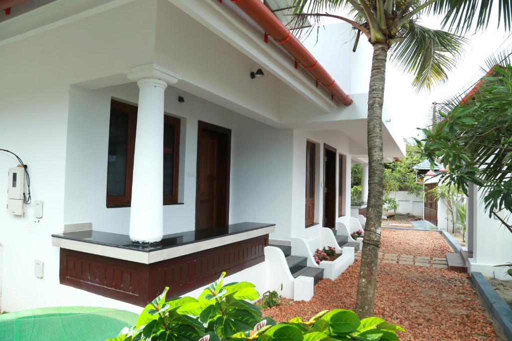 een wit huis met een palmboom in de tuin bij Alleppey - The Beach Home in Alleppey
