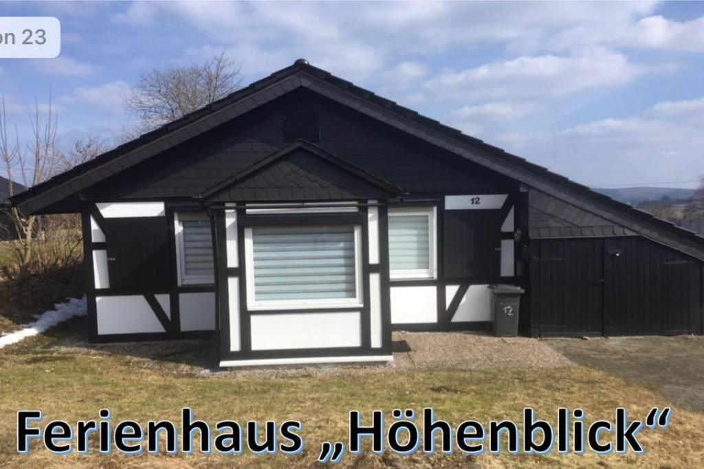 a black and white house with a garage at Ferienhaus Höhenblick in Winterberg-Langewiese in Winterberg