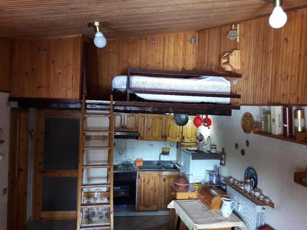 a kitchen with wooden cabinets and a bunk bed at Condominio La Betulla in Campo di Giove