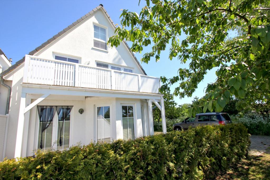 a white house with a car parked in the driveway at Ferienwohnung Neptun FeWo 01 - Terrasse, Garten in Drewoldke