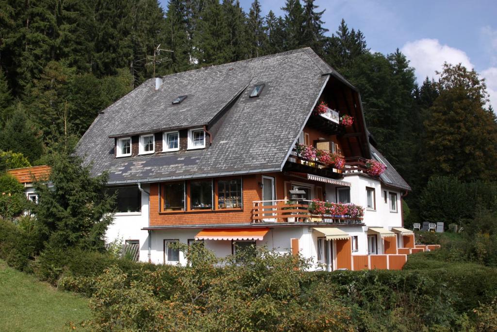 een huis met een zwart dak en bloemen op het balkon bij Hotel-Pension Thomé in Hinterzarten