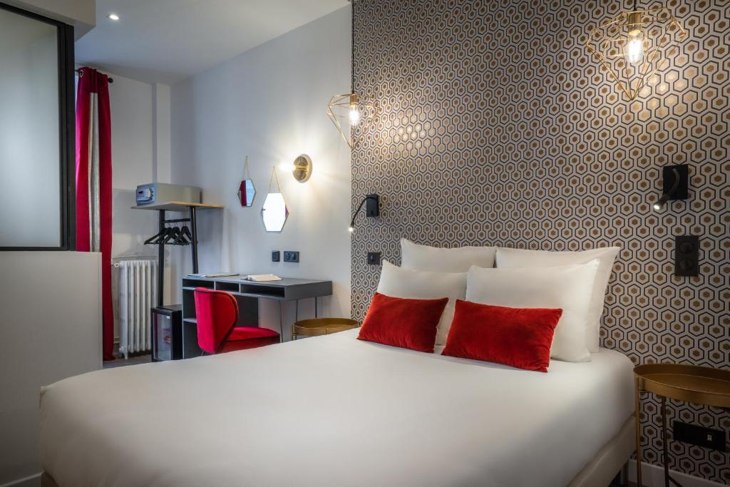 a bedroom with a large white bed with two red pillows at Hôtel Royal Opéra in Paris