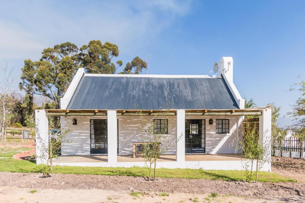 een klein wit huis met een metalen dak bij Druk My Niet Wine Estate in Paarl