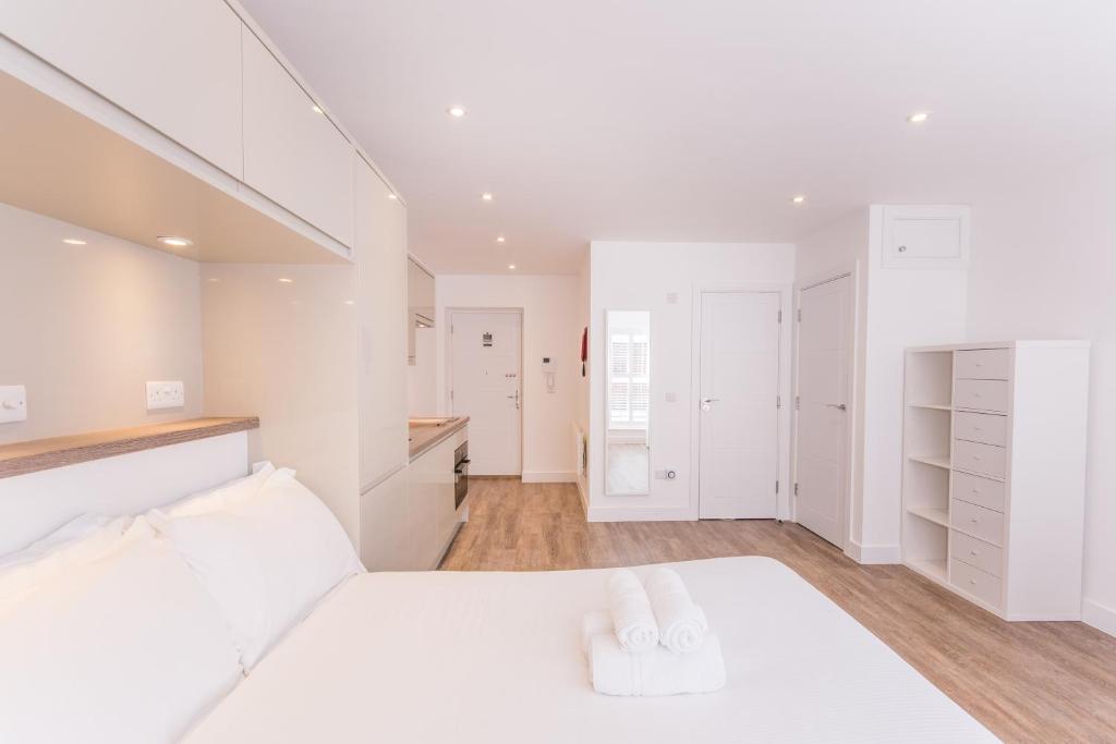 a white bedroom with white cabinets and a bed at Town or Country - Canute Studio in Southampton