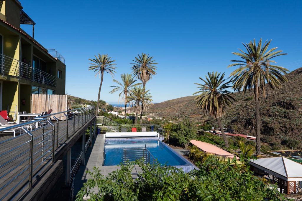 einem Pool an der Seite eines Gebäudes mit Palmen in der Unterkunft Holidays & Health in Finca Oasis - APART 6 in San Roque