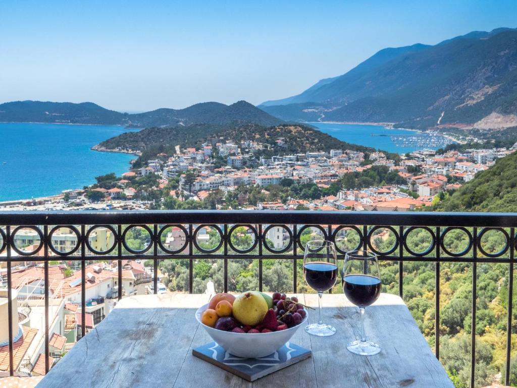a bowl of fruit on a table with two glasses of wine at Hideaway Penthouse Apartment in Kaş