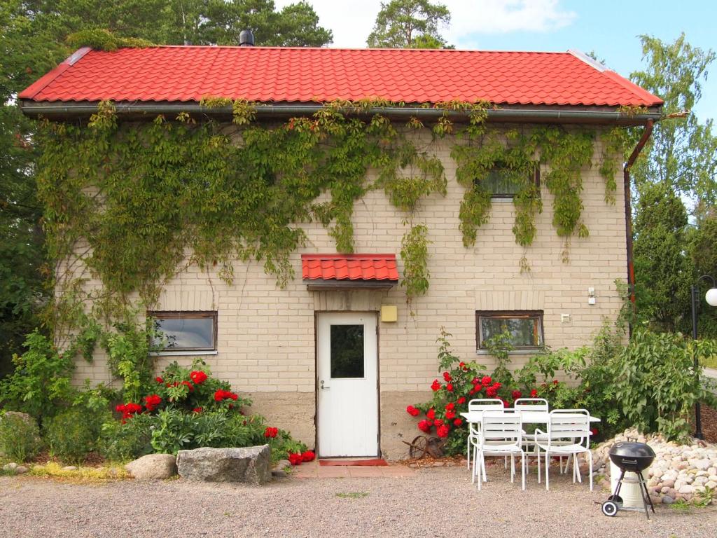 a house with a red roof and white chairs and flowers at Tammiston Apartments in Naantali