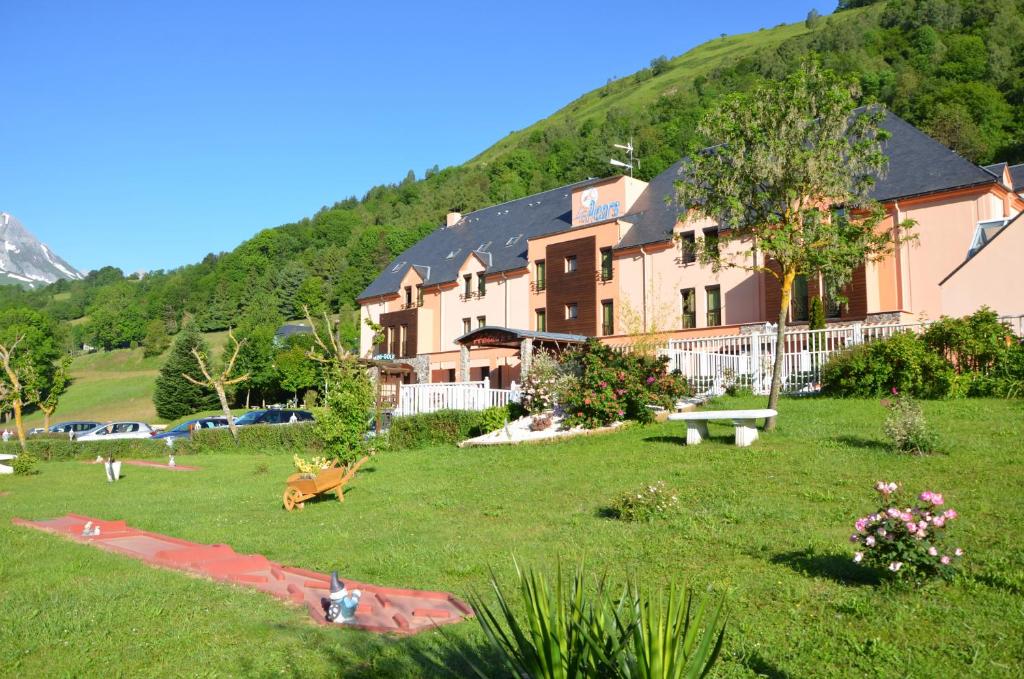 ein großes Gebäude auf einem Feld mit einem Hügel im Hintergrund in der Unterkunft Hôtel Le Picors in Aucun