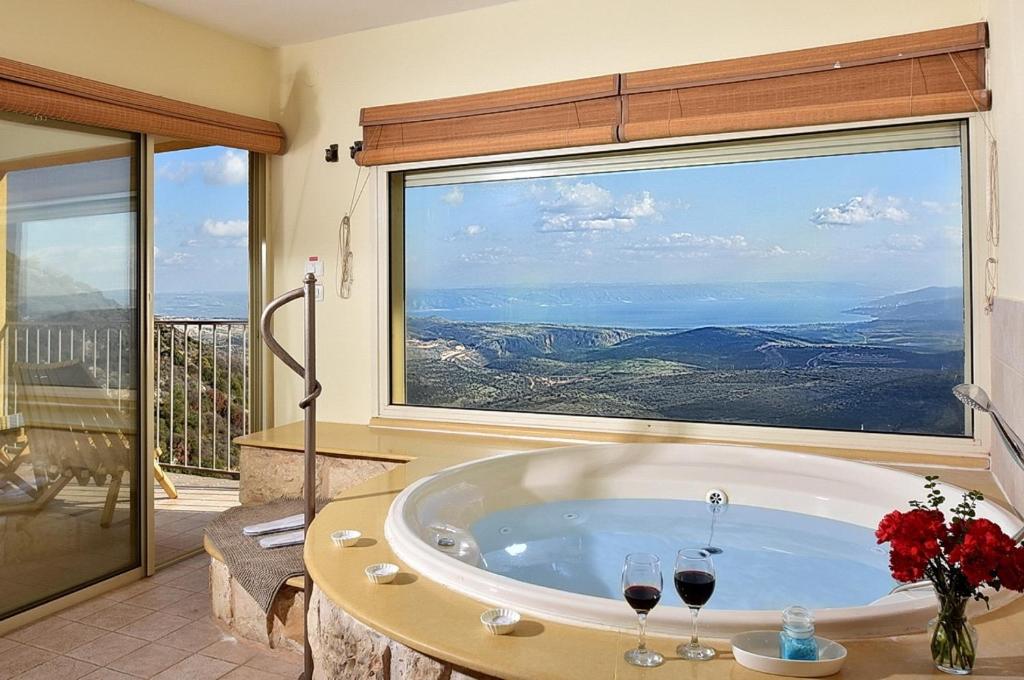 a bathroom with a tub with two glasses of wine at Nof 10 in Amirim