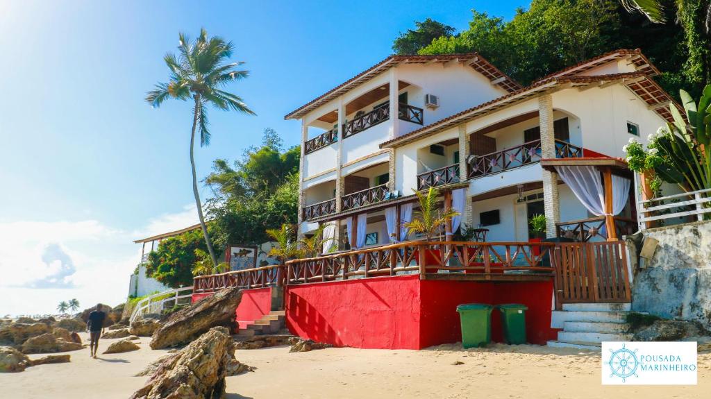 un edificio rojo y blanco en la playa en Pousada Marinheiro en Morro de São Paulo