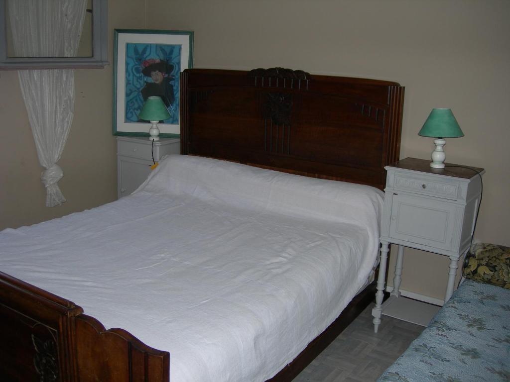 a bedroom with a large bed and a dresser with a green lamp at Appartement les rives de l’Ariège in Luzenac