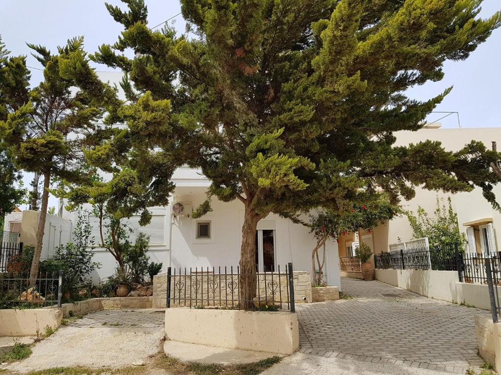 un albero di fronte a una casa con una recinzione di Sun Βy Τhe Sea 100m from the beach ad Agia Pelagia