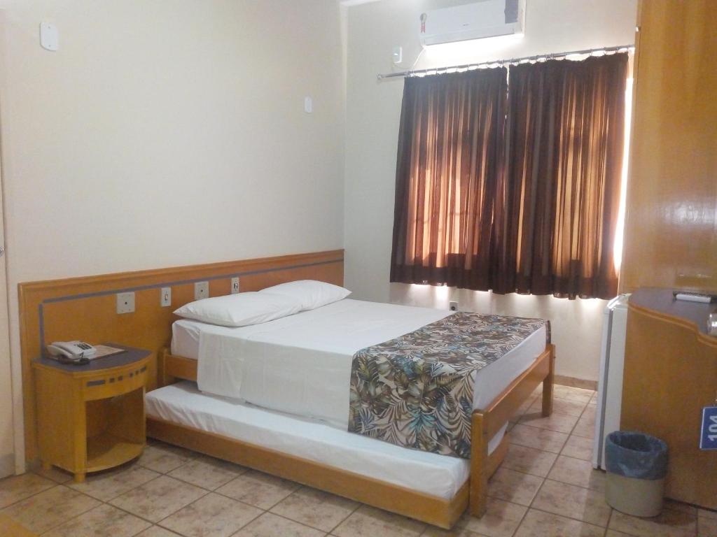 1 dormitorio con 2 camas y ventana en Hotel Nacional Service, en Goiânia