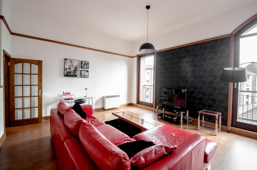 a living room with a red couch and a tv at City Centre Orange Apartments Bastille in Aberdeen