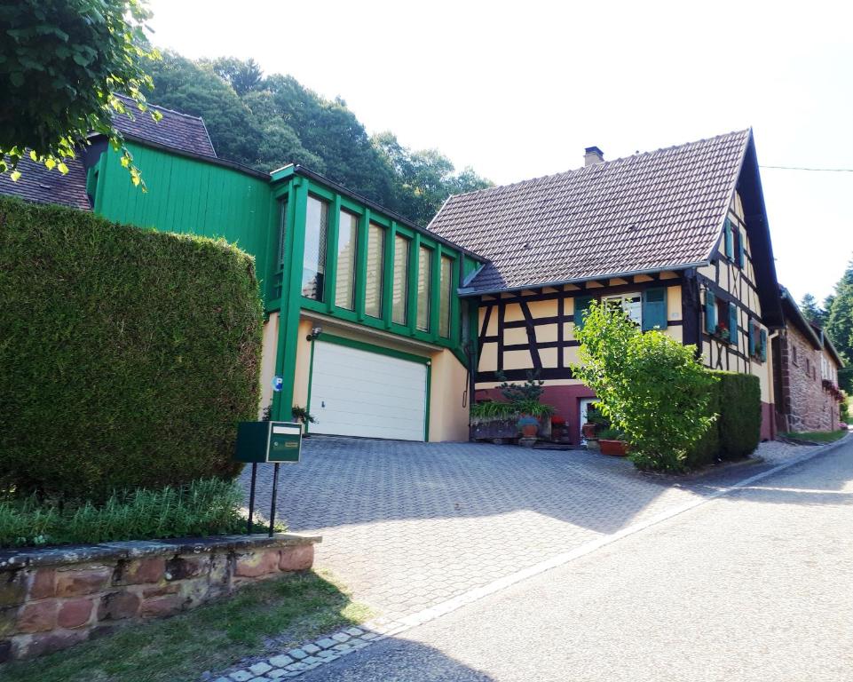 una casa con un edificio verde y blanco con garaje en Gîte du Windstein en Windstein