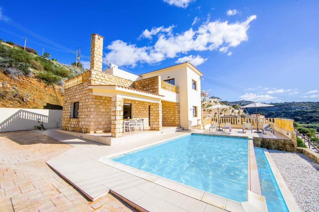 una villa con piscina frente a una casa en Aqua View, en Kissonerga