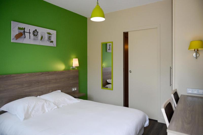 a green bedroom with a white bed and a table at Logis La Lentillere - Restaurant Côté Parc in Lalacelle