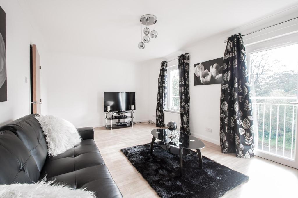 sala de estar con sofá de cuero negro y TV en Orange Town House - Shaw Road, Only 6 Minutes to City Centre, en Aberdeen