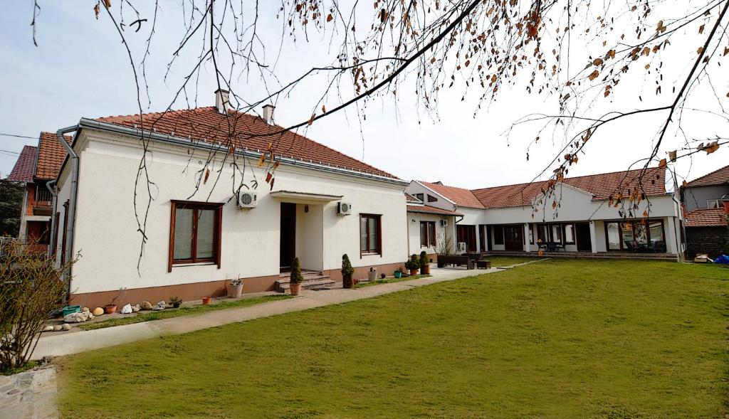 una casa blanca con un césped verde delante de ella en Mladenovic apartments en Kladovo