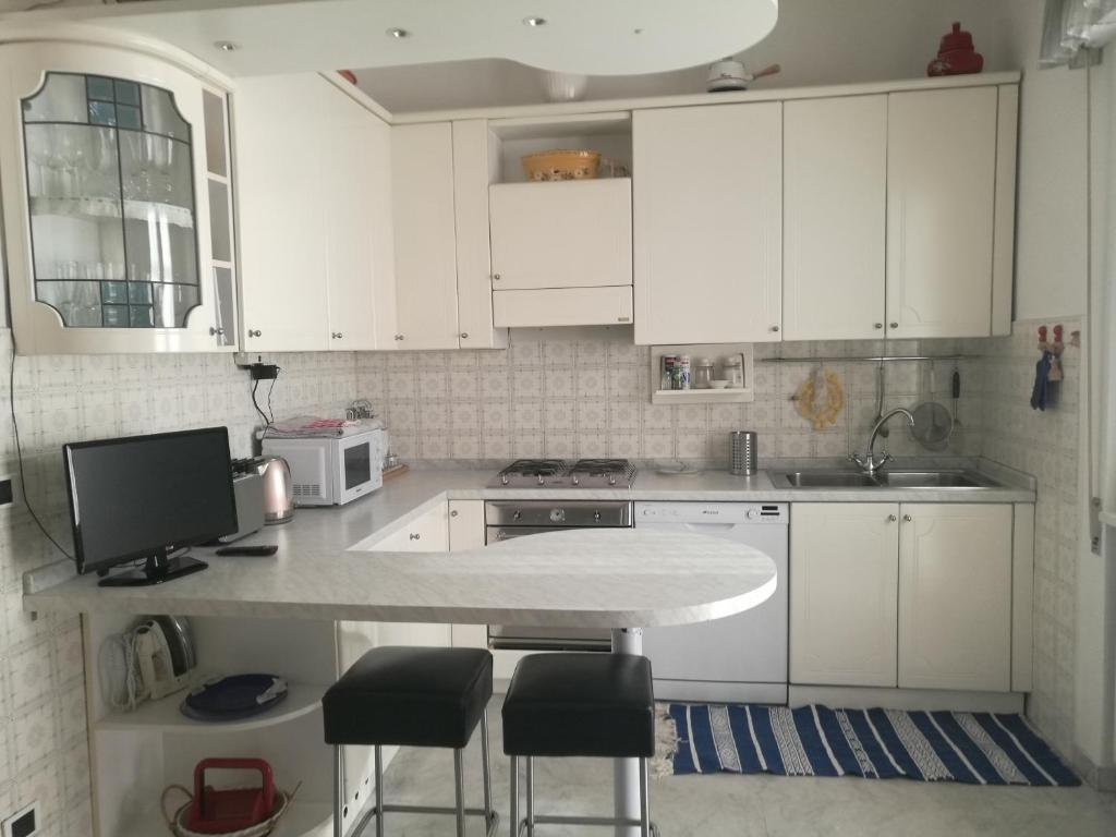 una cocina con armarios blancos y una barra con taburetes en Casa Santa Gemma, en Camaiore