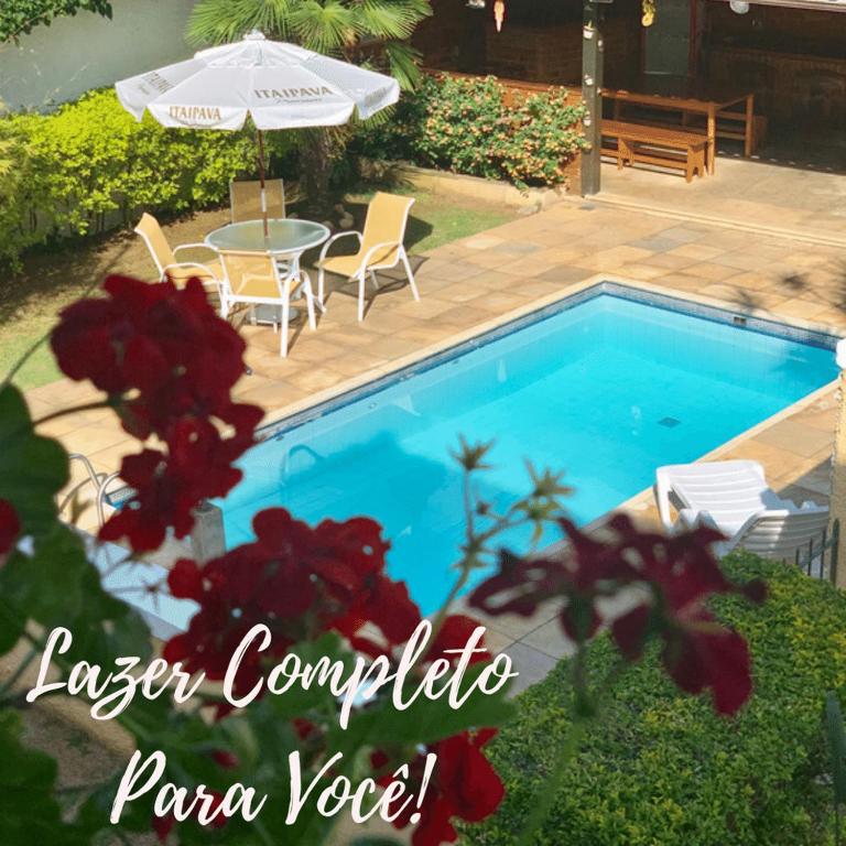 a swimming pool with a table and some red flowers at Casa do Pinheiro Petrópolis in Petrópolis