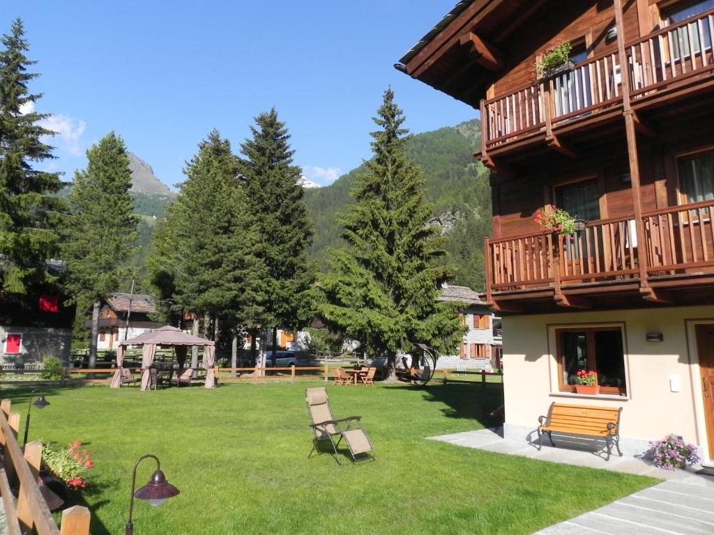 a building with a yard with benches and trees at Villa Americana Chambres d'Hotes in Champoluc