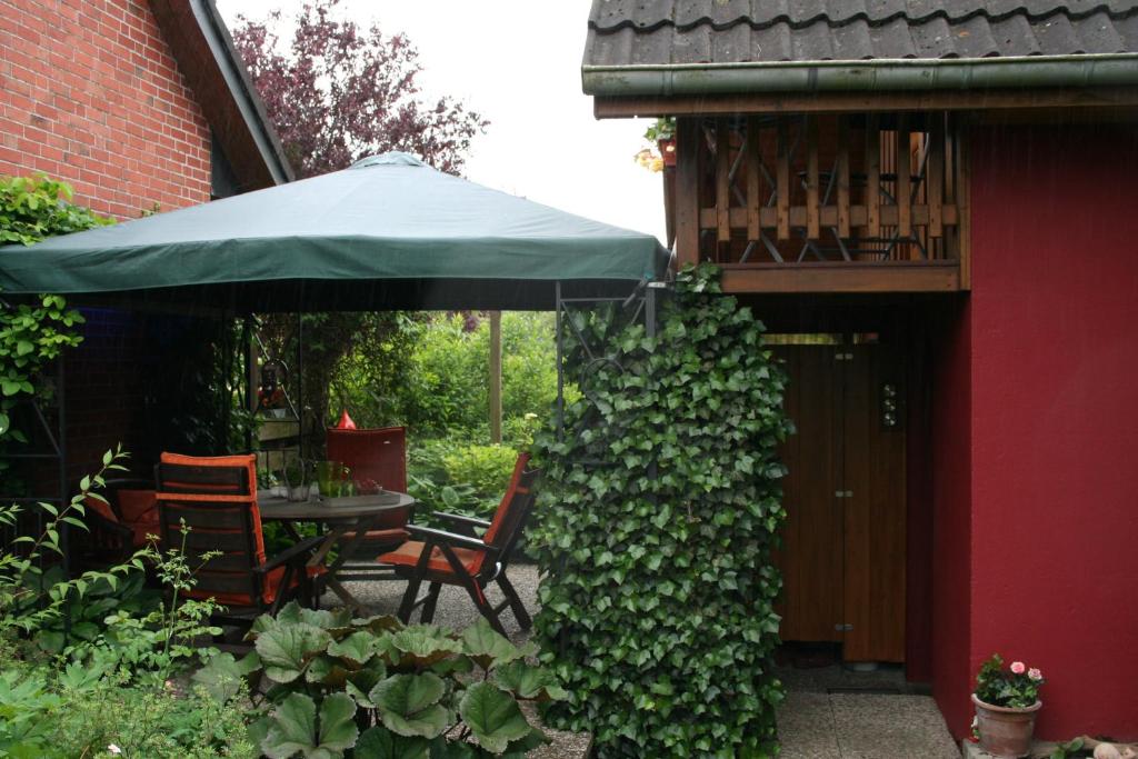 una mesa y sillas bajo una sombrilla en un jardín en Appartement Rose en Hechthausen