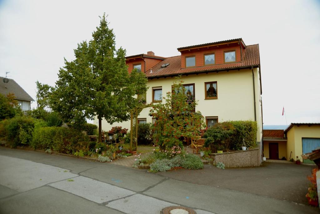 Maroldsweisach的住宿－Ferienwohnung Margit Altenstein，前面有树木和植物的白色房子
