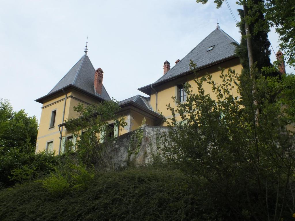 een geel huis met een grijs dak op een heuvel bij Chateau du Donjon in Drumettaz-Clarafond
