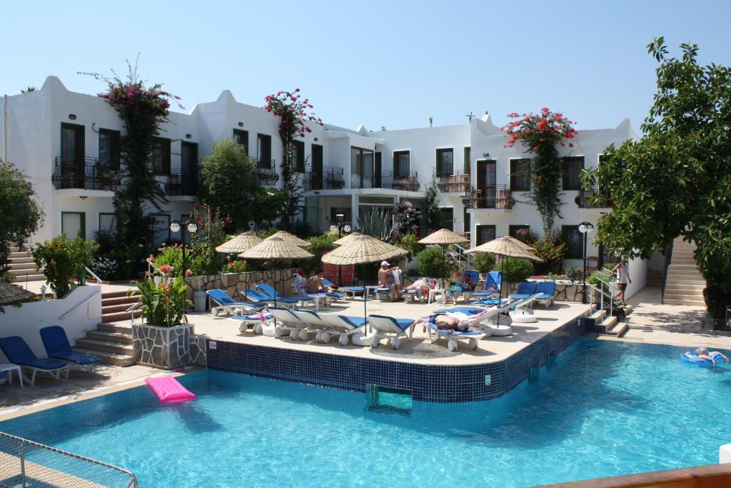 una piscina en un hotel con personas sentadas en sillas y sombrillas en Bronze Hotel, en Gümbet