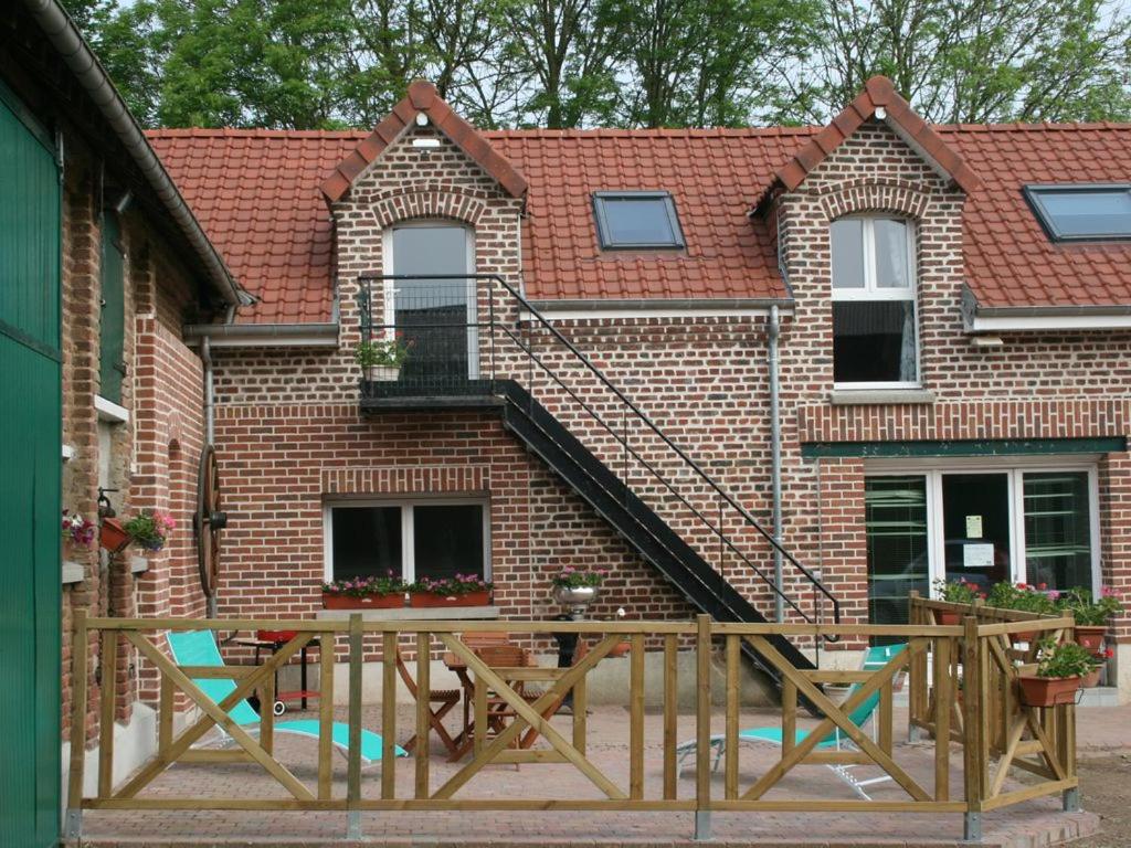 a house with a wooden deck with a staircase at Au gîte du treuil in Monchy-au-Bois