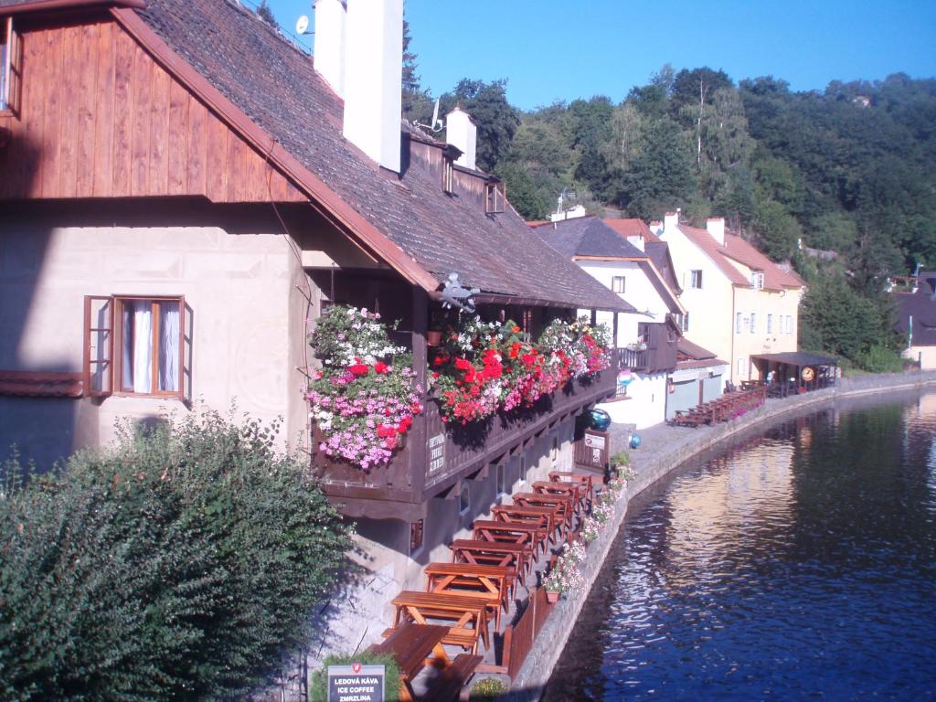 a building with flowers on the side of a river at Pension Meandr in Český Krumlov
