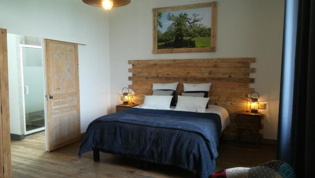 a bedroom with a bed with a wooden headboard at Le Presbytère de Saint Malon in Saint-Malon-sur-Mel