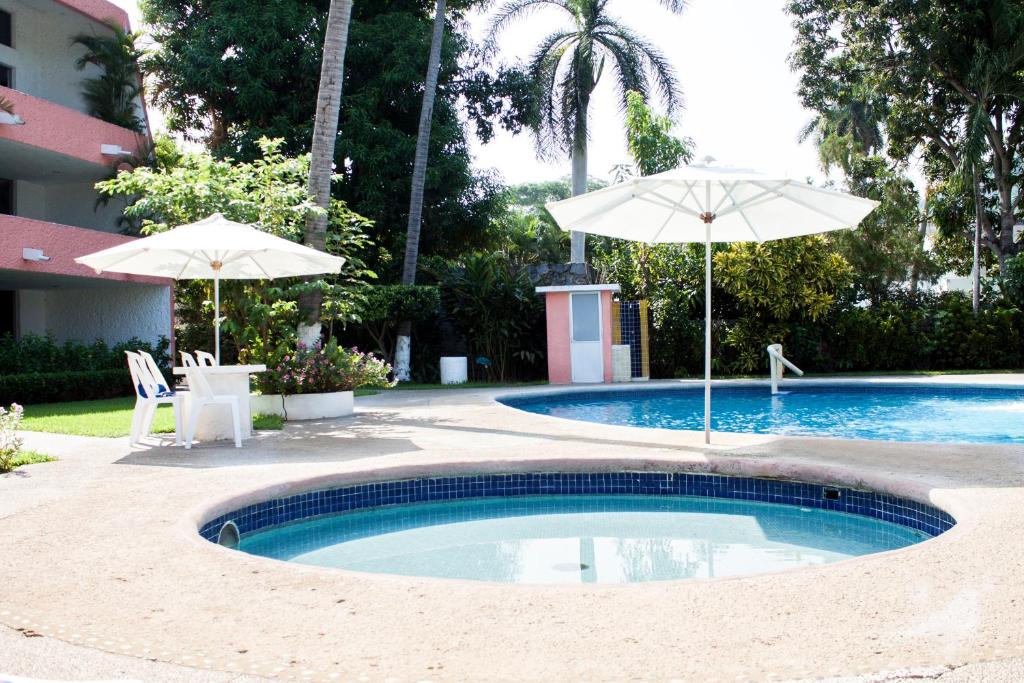 a swimming pool with two umbrellas next to a building at Coral Ixtapa in Ixtapa